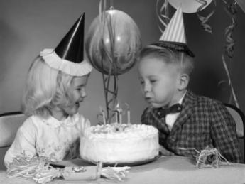 1960s-boy-blowing-out-candles-on-birthday-cake